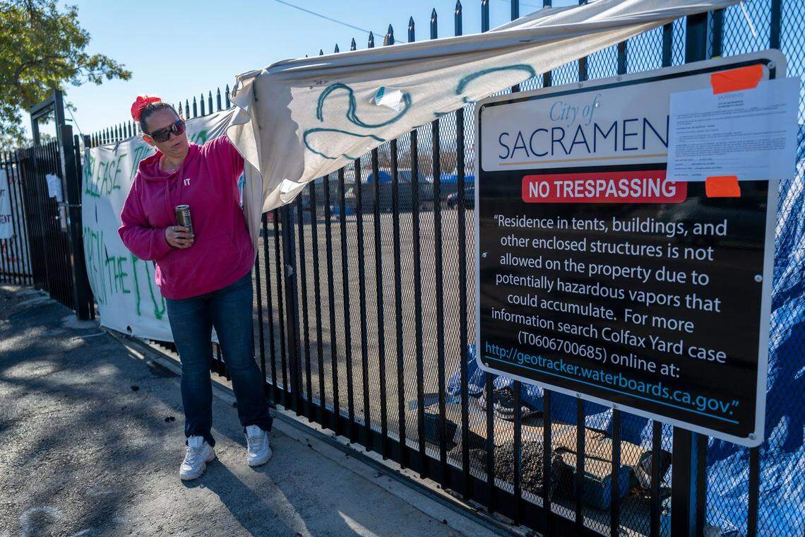 Homeless camper Danyell Mayberry, 42, shows the notice that Sacramento City posted on the fence of “Camp Resolution,” in a self governing homeless encampment at Arden Way and Colfax street in North Sacramento on Tuesday. City officials have decided not to clear the homeless encampment — for now.