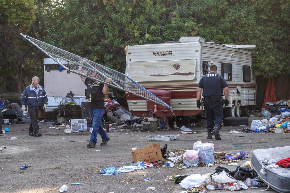 Sacramento city building inspector Jason Martinoni carries a fence away Wednesday during a homeless encampment sweep on 1st Avenue in Sacramento. The women who live in the trailer said they felt safe there with their dogs, and worried about where they would relocate. City officials proposed the tent-only Miller Park Safe Ground site.