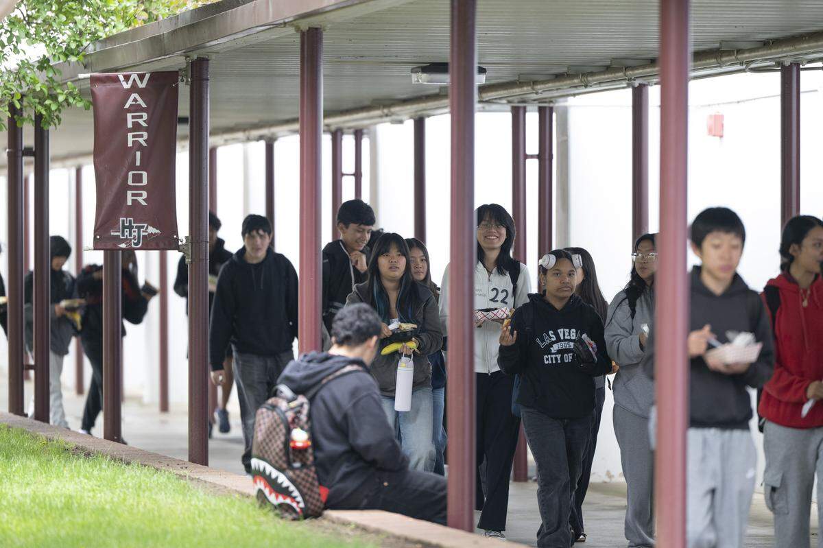 Students walk beside a banner that reads “Warrior” with a spear at Hiram Johnson High School in Sacramento on Tuesday.