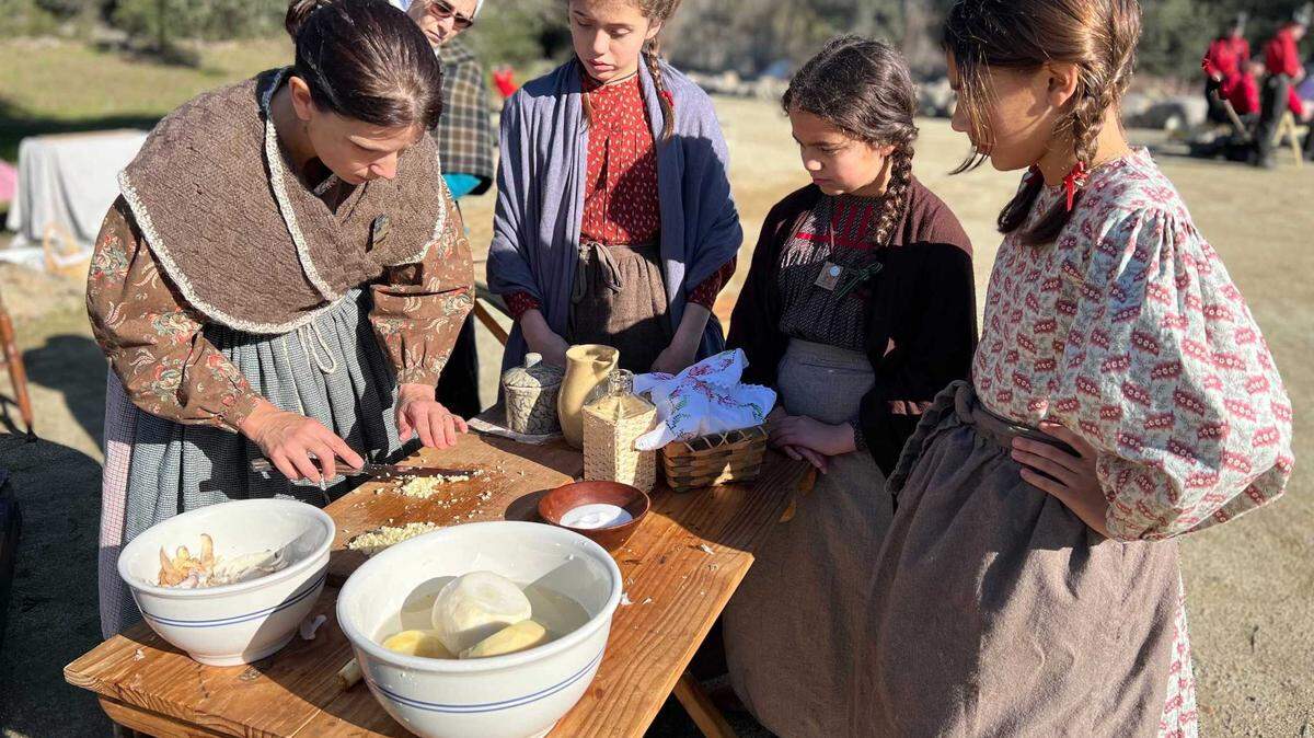 Audrey Ortega, left, dressed in traditional pioneer clothes, teaches children how to make garlic paste Saturday at Marshall Gold Discovery State Historic Park. Ortega said women who sold food to miners in the mid-1800s made as much money as doctors.
