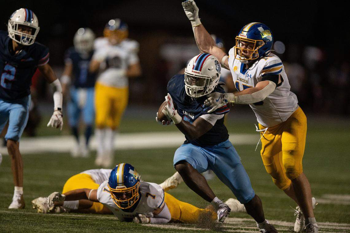 The Destiny Christian Lions’ Caleb Hill (0) is tackled by the Linden Lions’ Braden Busalacchi (15) after a long gain negated by a penalty on Friday.