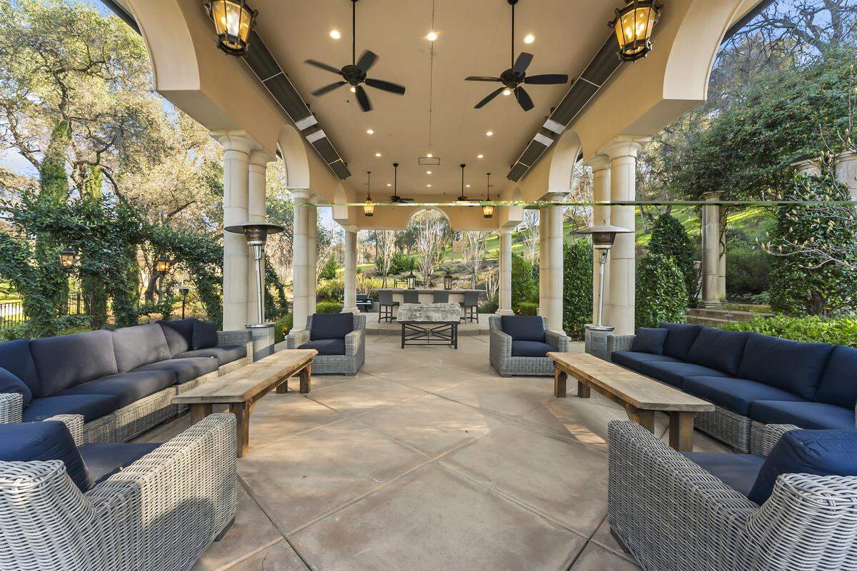 The owners built an outdoor entertaining zone with its own name and a menu of party-ready features: outdoor kitchen, built‑in fireplace, pizza oven and big seating area.