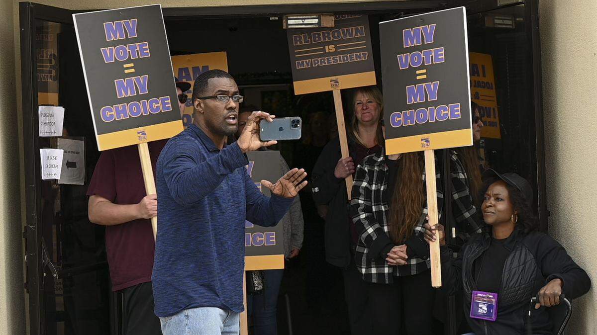 SEIU Local 1000 president Richard Louis Brown stands with supporters on Saturday, March 5, 2022, as he holds his phone up to do a live video in front of the union’s headquarters in downtown Sacramento. The union’s board of directors voted to remove him from office on Jan. 7, 2023 after an independent investigation found he misused his powers as president.