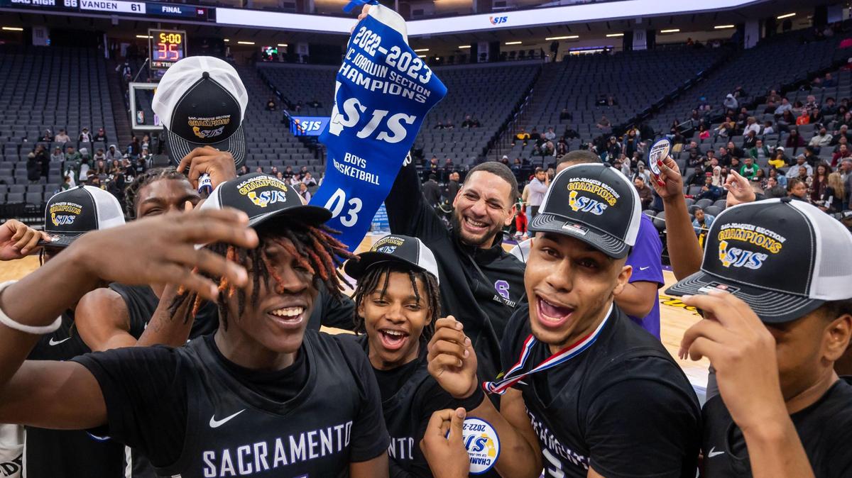 Sacramento Dragons head coach Matt Johnson, center, holds up the CIF Sac-Joaquin Section Division III high school boys basketball title after his team defeated the Vanden Vikings in the final game Saturday, Feb. 25, 2023, at Golden 1 Center in Sacramento.