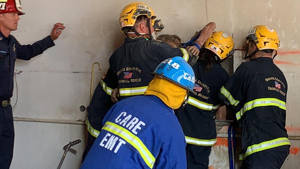 Firefighters cut through a wall Tuesday to rescue a nude woman trapped in a 10-inch gap between two Santa Ana, California, buildings. 