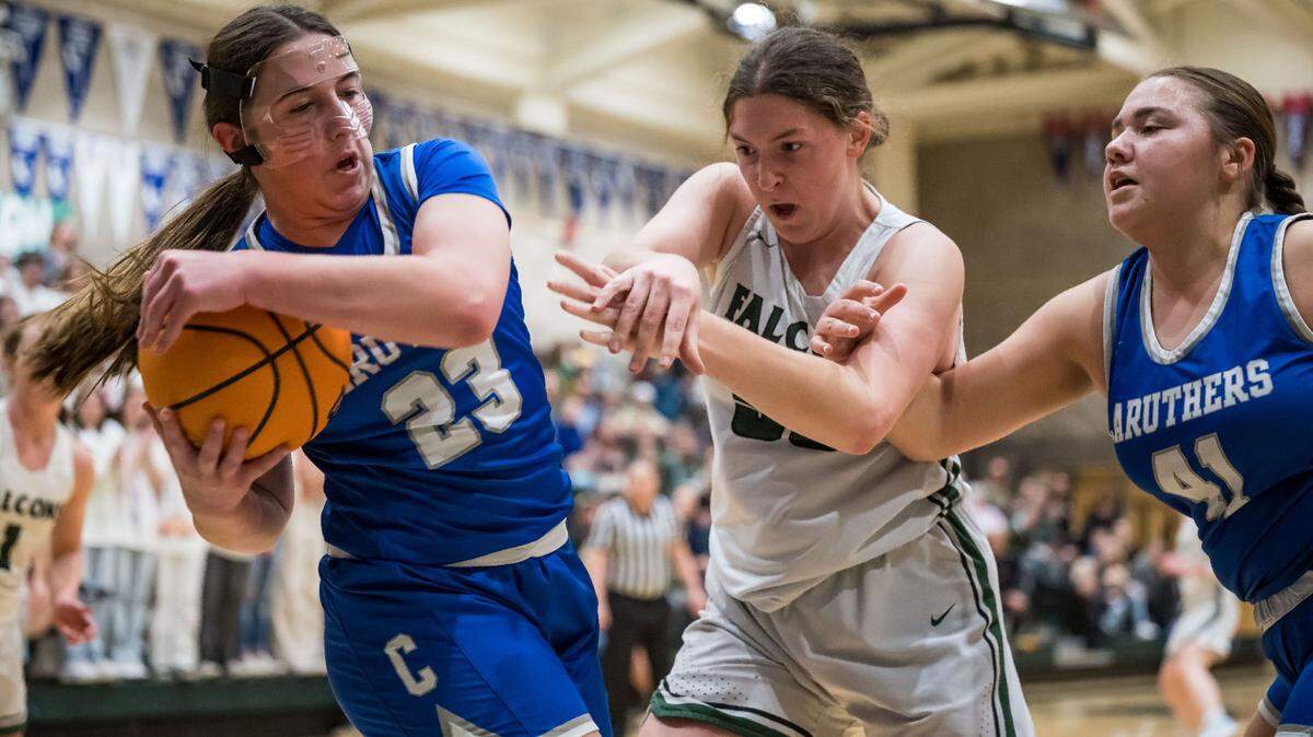Caruthers Blue Raiders forward/guard Emmi Almeida (23), left, and center Mia Nola (41) try to keep the ball from Colfax Falcons center Juliette James (55) during the first quarter of the CIF Northern California Division III high school girls basketball championship game Tuesday, March 7, 2023, at Colfax High School.