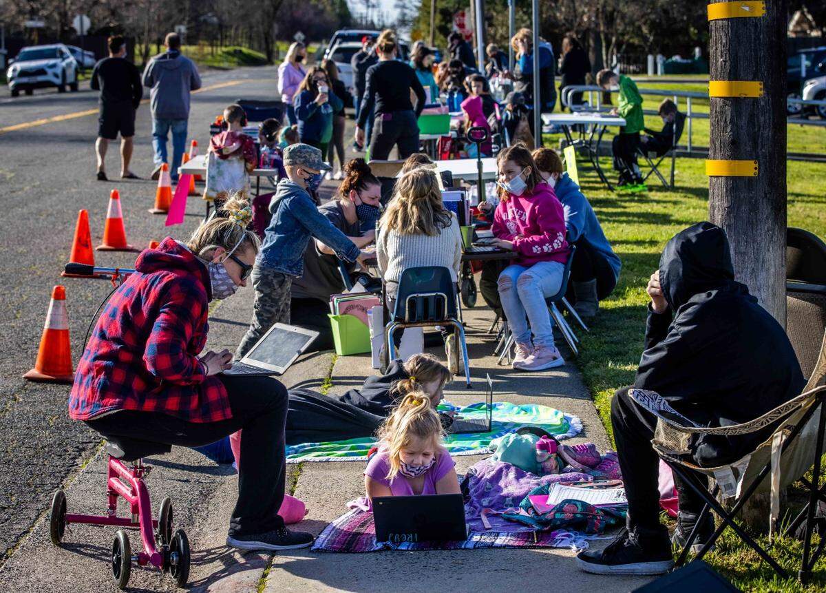 Freyja Strandberg, 6, center, does schoolwork on her laptop near Oakview Community Elementary in Orangevale on Tuesday, Feb. 23, 2021, as parents and children participate in a sit-in demonstration protesting distance learning at San Juan Unified School District, demanding for in-person learning.