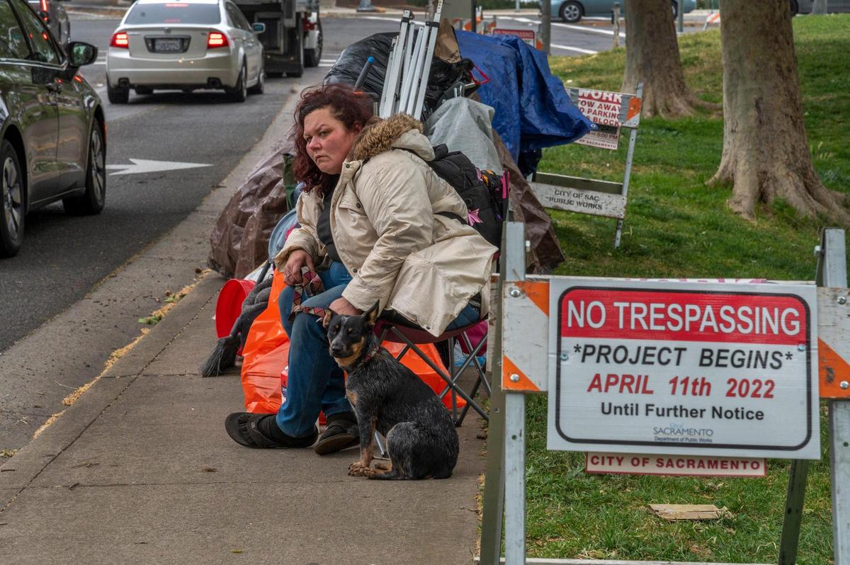 Dena Vickroy, 37, waits with her cattle dog she rescued from a trash can, for someone from the county to call her after she was told she had to vacate the Fair Oaks and Howe homeless encampment in Sacramento on Monday. As she waited she tried to call a guy named Justin from the county who she said was going to help her find housing. It had just started to rain and she said if he didn’t call her she had no idea where she would go.