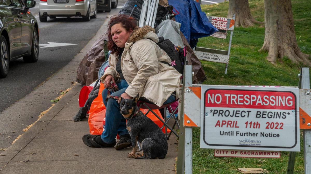 Dena Vickroy, 37, waits with her cattle dog she rescued from a trash can for someone from the county to call her after she was told she had to vacate the Fair Oaks and Howe homeless encampment in Sacramento on Monday, April 11, 2022. As she waited she tried to call a guy named Justin from the county who she said was going to help her find housing. It had just started to rain and she said if he didn’t call her she had no idea where she would go.