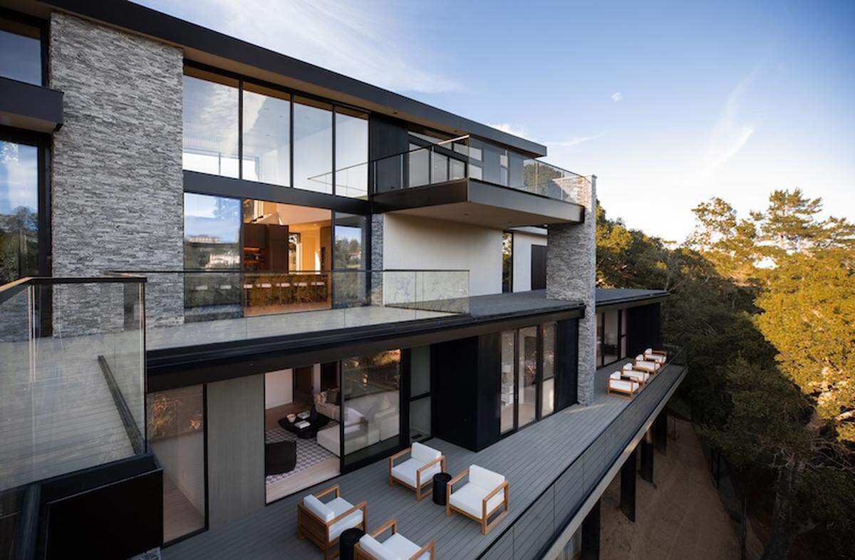 Walls of glass and soaring ceilings flood the open-concept living space with natural light and treetop views.