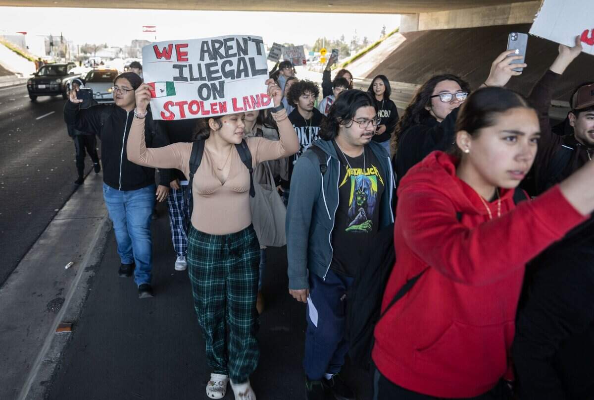 Students from Hiram Johnson High School in Sacramento hold signs as they walk under the Highway 50 overpass during a walkout Tuesday in protest of the Donald Trump administration.