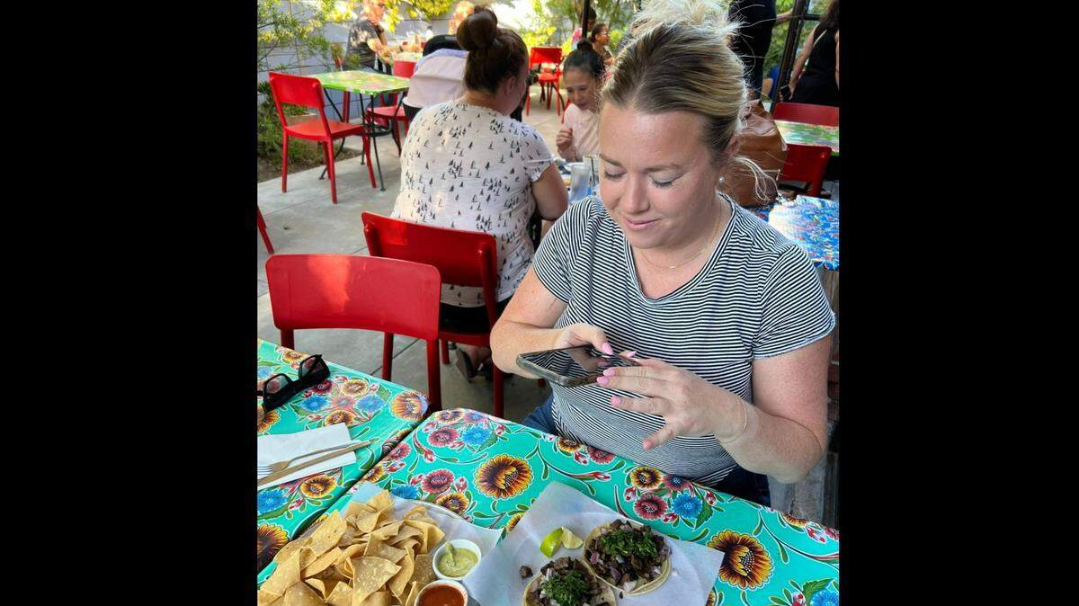 Maddy Eccles, a Sacramento-based influencer with more than 100,000 followers, uses her smartphone to capture a picture of a meal at La Venadita, a restaurant in Oak Park on August 9, 2023. 