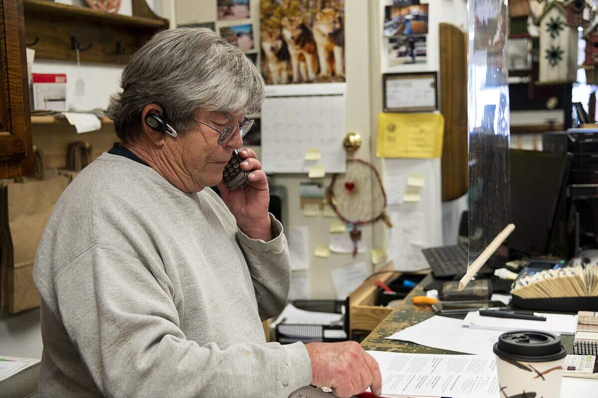 A hanging plastic screen separates Toan Doan, owner of Country Wood Furniture, from his customers at the cash register in Grass Valley on Monday, May 18, 2020, during the coronavirus pandemic.