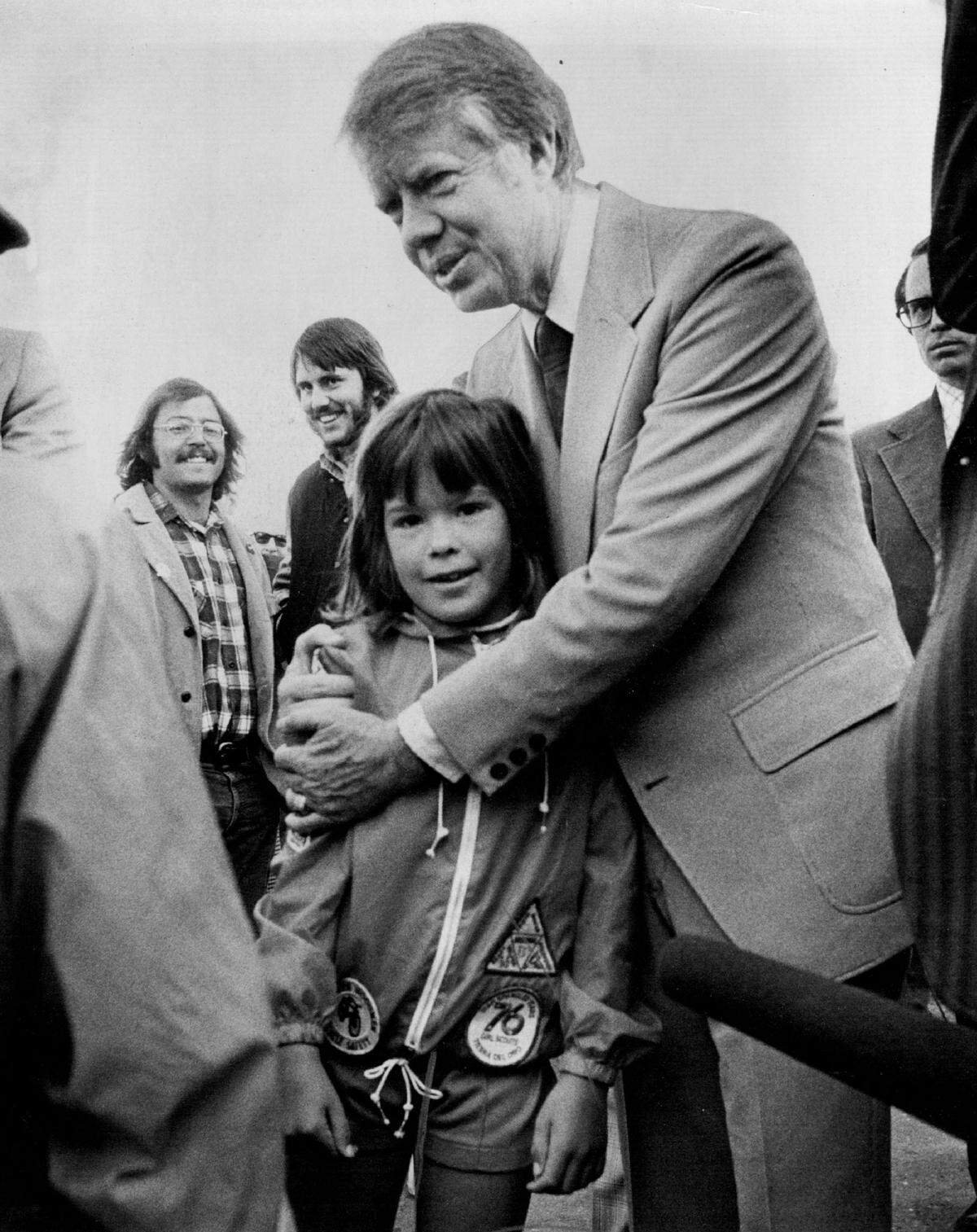 Jimmy Carter talks to Penny Fererda, 7, the daughter of a Sacramento Municipal Utility District employee, during a campaign visit on May 31, 1976.