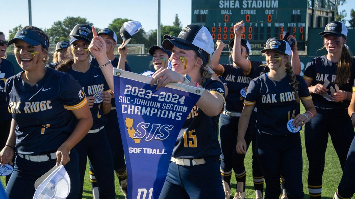 Oak Ridge’s Jess Szelenyi (15) celebrates with the Sac-Joaquin Section championship banner after the Trojans beat Whitney in the Division I final in May at Sacramento State.