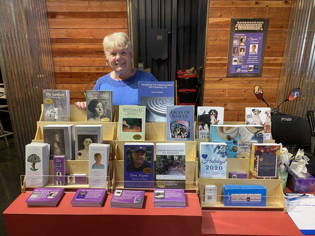 Sharon S Darrow posing with her books at the California State Fair Authors Booth.