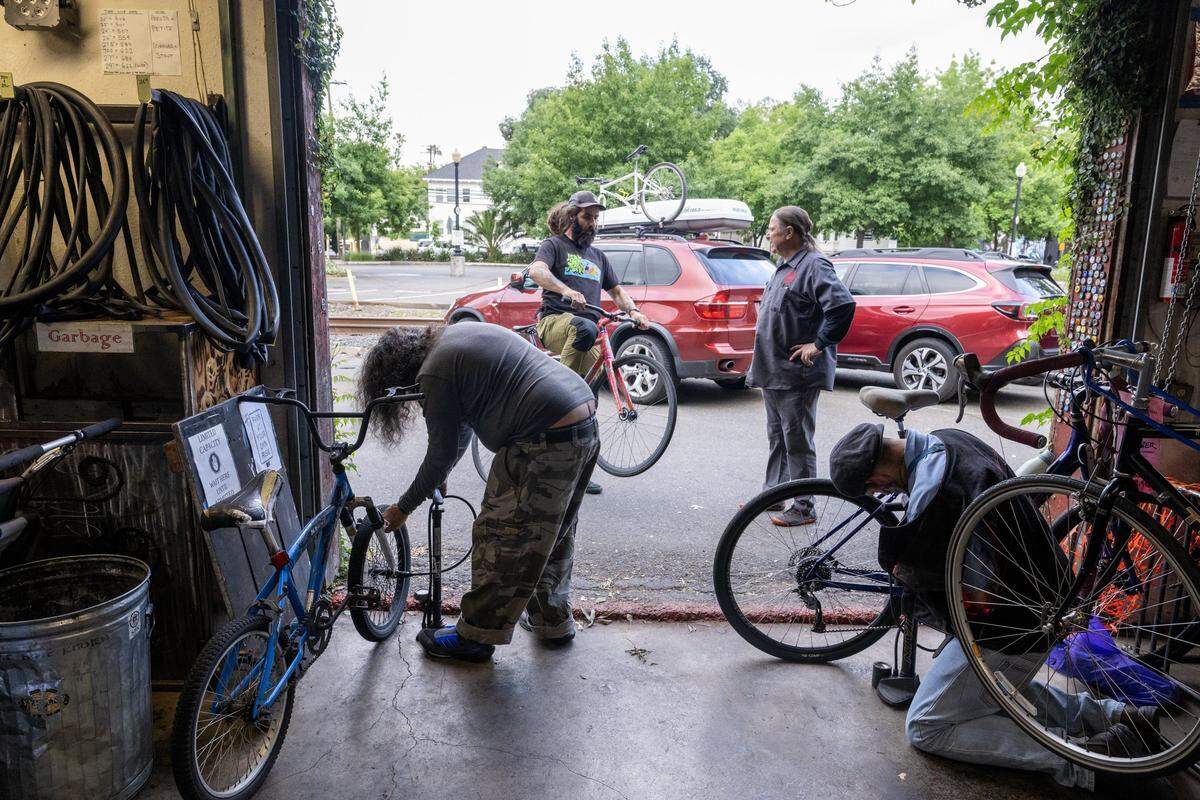 Bike owners come through the rollup door to work on their bikes at the Sacramento Bicycle Kitchen on Tuesday, May 5, 2026.