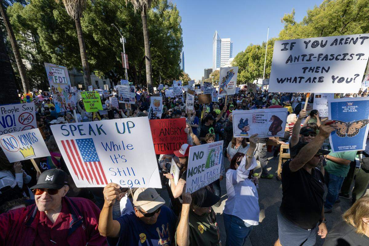 Demonstrators hold signs during the "No Kings" protest at the state Capitol in Sacramento on Saturday, Oct. 18, 2025.