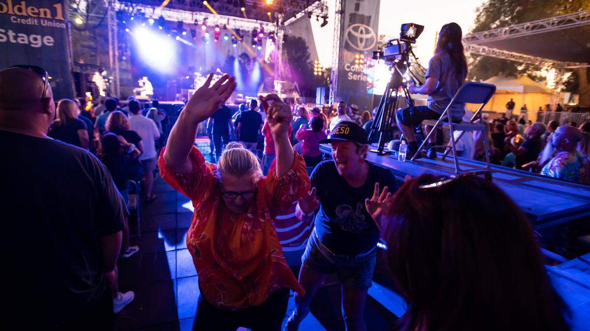 Cynthia Lynch, left, of Sacramento, raises her arms and dances along with a group of fellow fans as Queen Nation, a Queen tribute band, performs Crazy Little Thing Called Love on the Golden 1 Stage during the California State Fair at Cal Expo on Tuesday, July 26, 2022, in Sacramento. On Wednesday, the fair announced Third Eye Blind will be taking the stage in 2023.