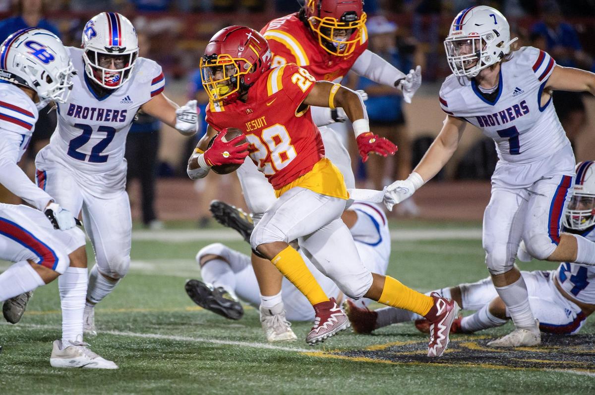 Jesuit’s Johnnie Brannon IV (28) runs the ball against Christian Brothers in the Holy Bowl in 2022 at Hughes Stadium.