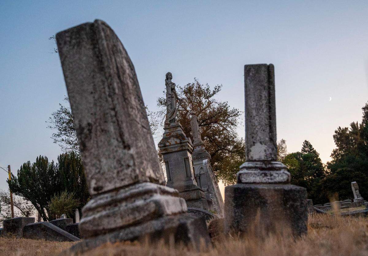 Headstones that date back to mid-19th century stand among large, statue monuments Wednesday at Sacramento’s Old City Cemetery.