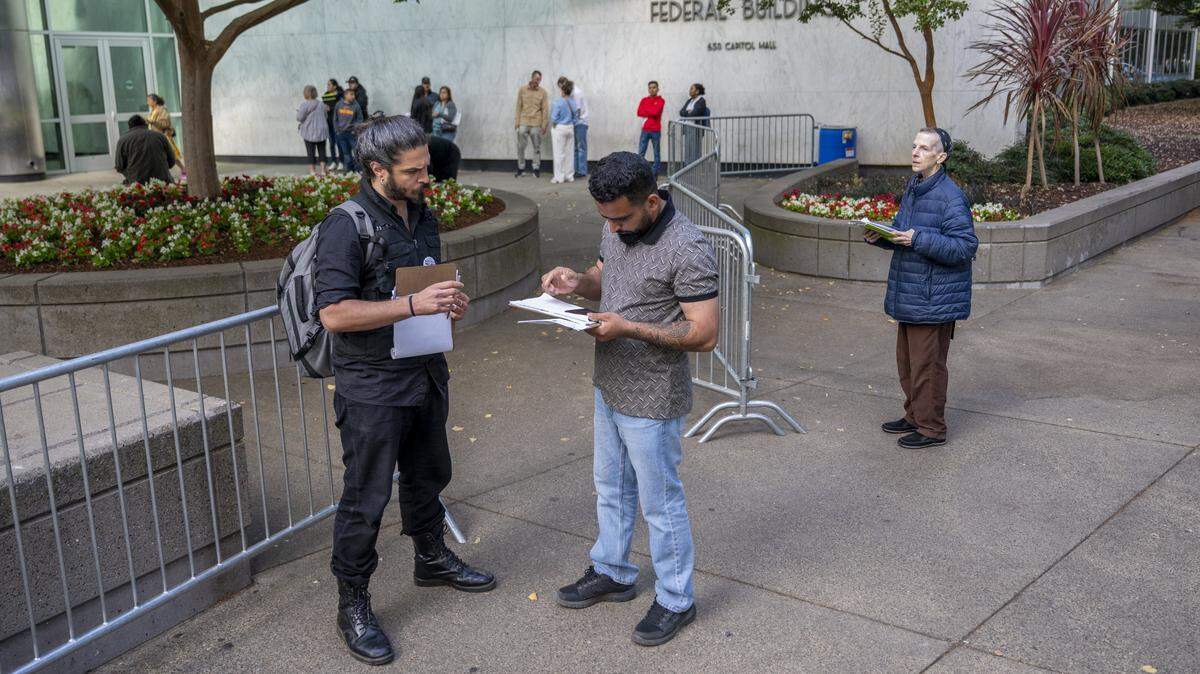 Niko Volonakis greets and checks in an individual who is meeting with immigration authorities outside the John E. Moss federal building in downtown Sacramento on Tuesday, July 22, 2025. Individuals may have an immigration check-in, interviews, or court hearings.