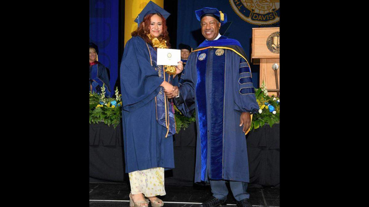 Author Ruby Ceja shakes hands with UC Davis Chancellor Gary May during her graduation ceremony.
