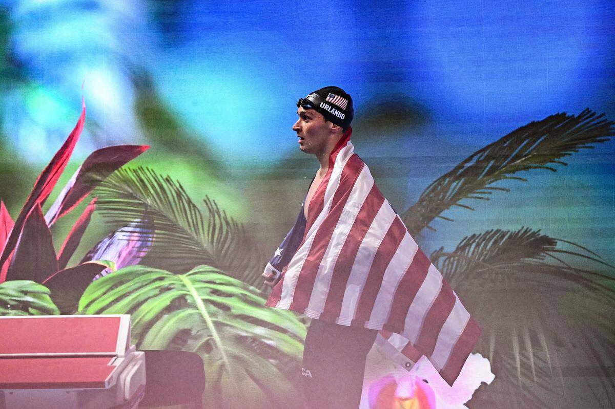 US' swimmer Luca Urlando celebrates with the United States flag after winning the final of the men's 200m butterfly swimming event during the 2025 World Aquatics Championships in Singapore on July 30, 2025. (Photo by MANAN VATSYAYANA / AFP via Getty Images)