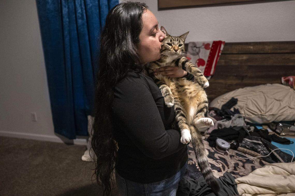 Sacramento resident Damaris Bello, 22, kisses her mother’s cat, Tiger, on Friday as she prepares to depart to Mexico to help her recently deported mother. 