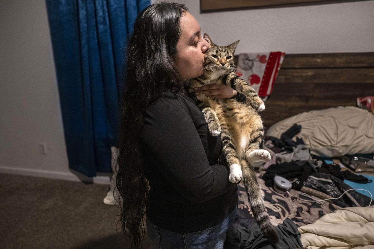 Sacramento resident Damaris Bello, 22, kisses her mother’s cat, Tiger, on Friday as she prepares to depart to Mexico to help her recently deported mother. 
