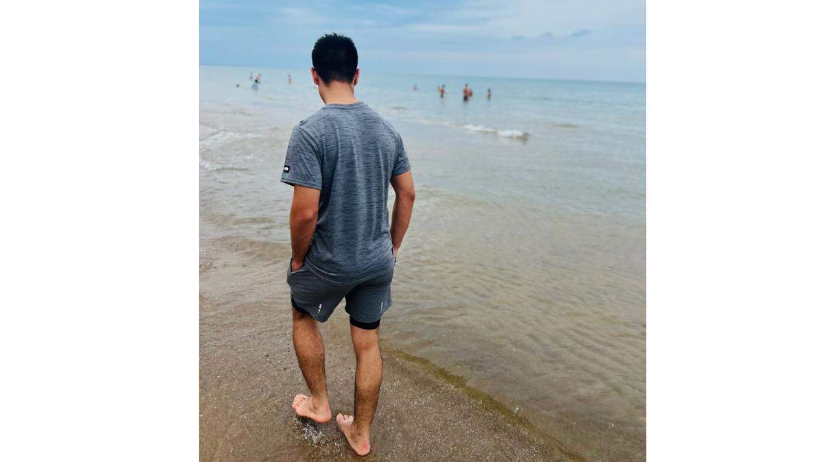 Rafi, an immigrant from Afghanistan, walks along the beach.