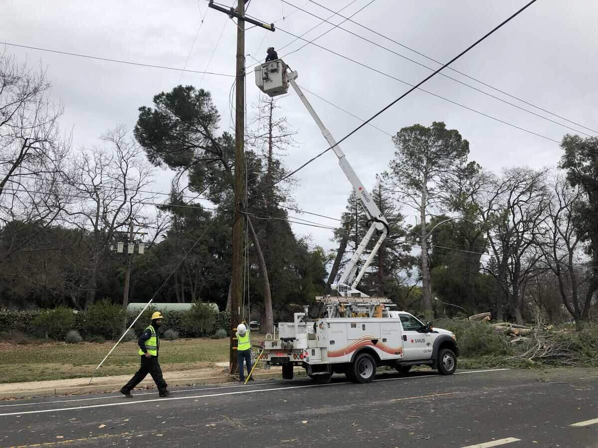 SMUD line foreman Alfonso Davila, left, crosses the street to supervise power line repairs on Sutterville Road in Land Park on Jan. 2. SMUD said that over 90 trees have been cleared thus far since the storm started on Dec. 31, 2022.