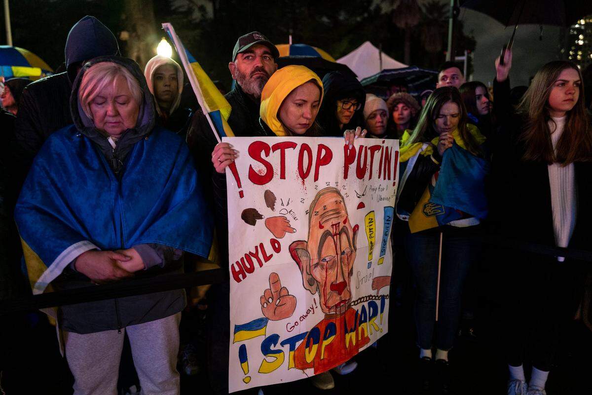 A tear falls on the cheek of Yuliia Apykova, from Ukraine, as she holds a flag and poster alongside her husband Timur Apykova, from Russia, at the state Capitol on Friday. The couple, who arrived in Sacramento 10 months ago, were participating in a moment of prayer.