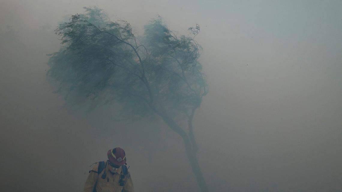 A firefighter braves gusty winds as heavy smoke from the Silverado Fire fills the air Monday in Irvine. A fast-moving wildfire forced evacuation orders for 60,000 people in Southern California on Monday as powerful winds across the state prompted power to be cut to hundreds of thousands to prevent utility equipment from sparking new blazes.