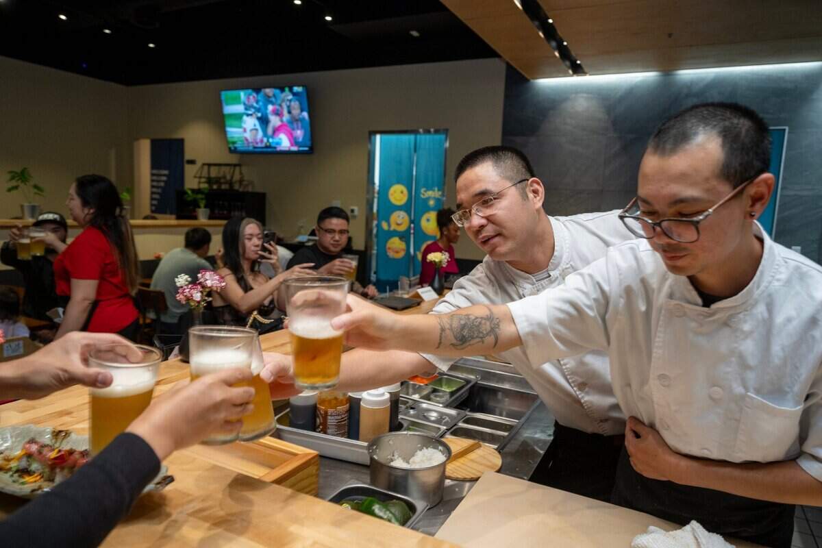 Chef Jun, center, and Chef Lu toast with patrons last month at Chef Frank Japanese Cuisine in North Natomas.