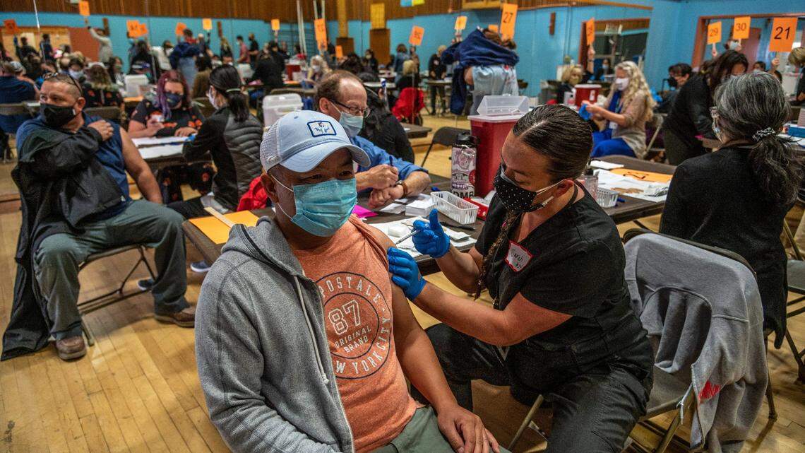 Chia Lor receives the Pfizer coronavirus vaccine from nurse Sarah Smoot at Burbank High School on Tuesday, April 13, 2021. The clinic had to switch from the Johnson & Johnson vaccine after U.S. health officials paused its use Tuesday because a rare blood clotting disorder was found in six recipients.