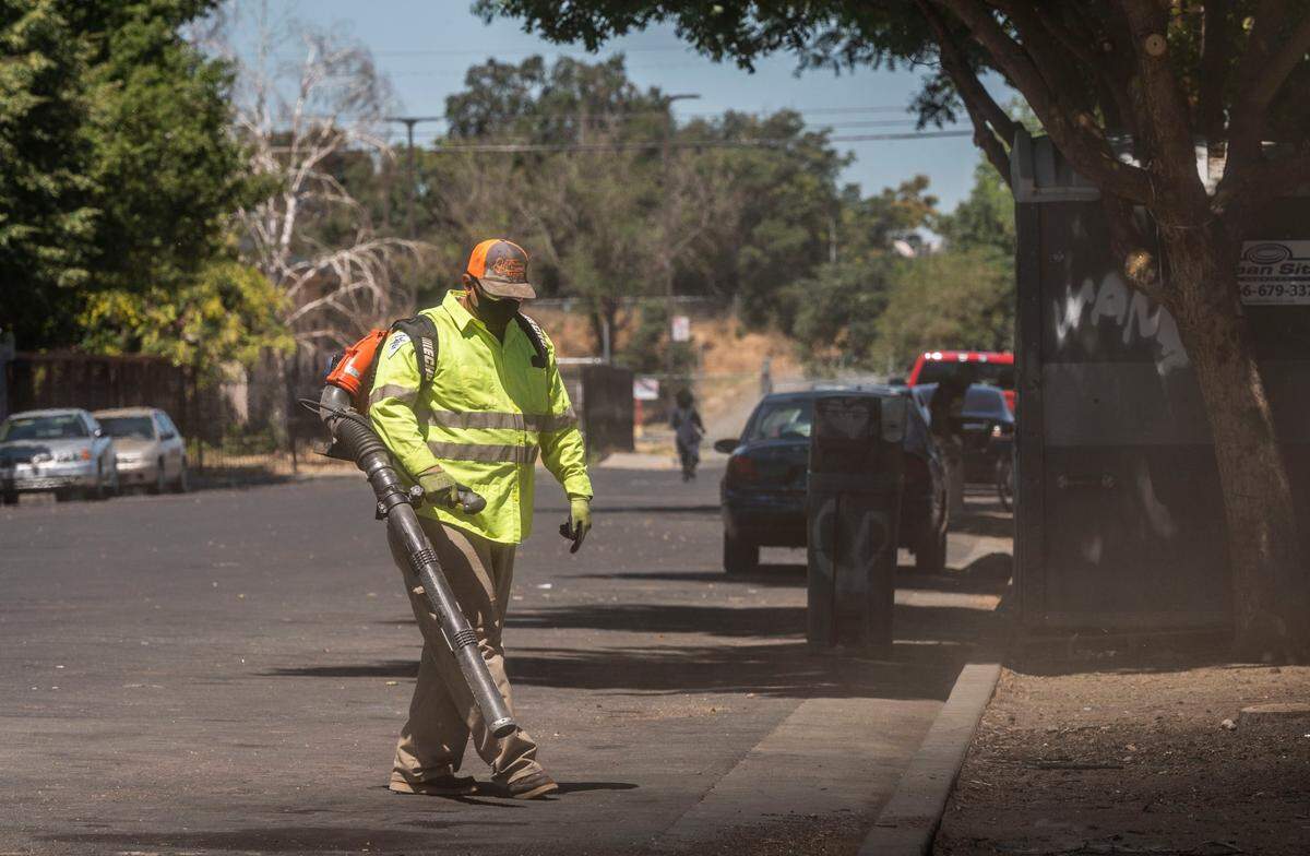 Jesse Yniguez, a formerly homeless Sacramento resident, cleans a section of A Street in the River District in June after an encampment-related fire burned the area. The business improvement district employs some unhoused residents to help improve the community and find them more permanent housing.