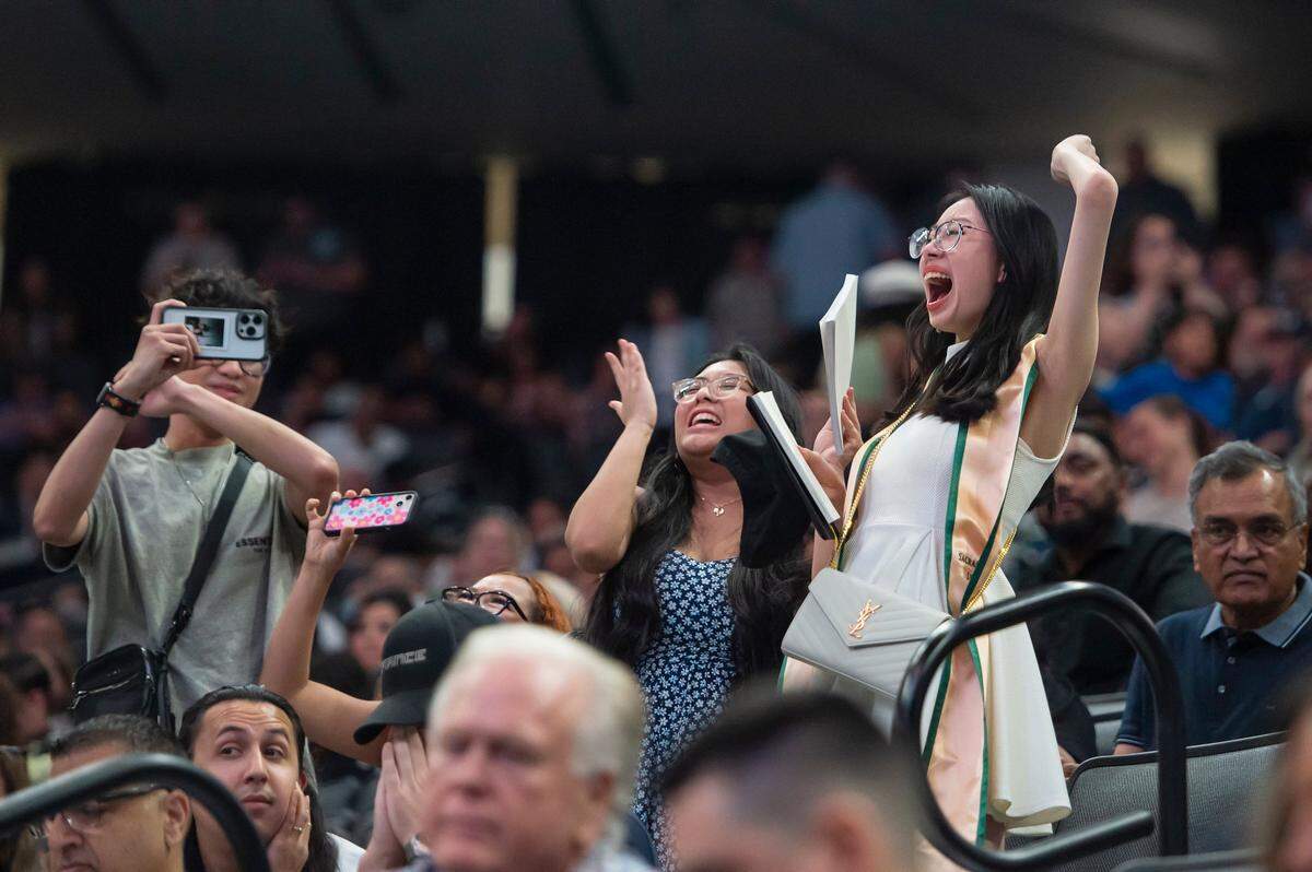 Two women cheer for a graduate during the Sacramento State College of Business commencement on Friday.
