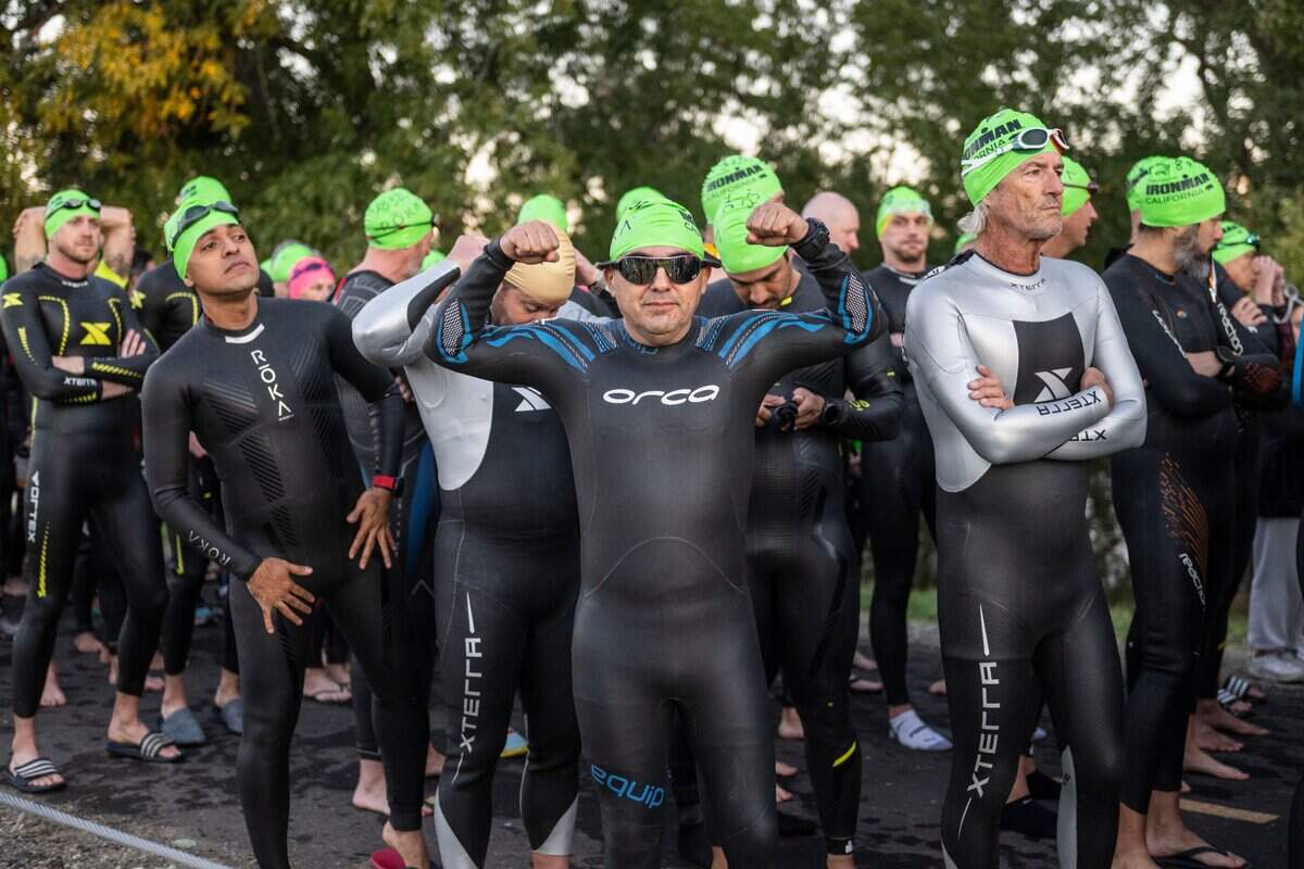 Jorge Alvarado of Orizaba, Mexico, flexes his muscles in his wetsuit as he prepares to start the Ironman California triathlon with a swim in the American River from Township 9 Park in Sacramento on Sunday, Oct. 23, 2022.