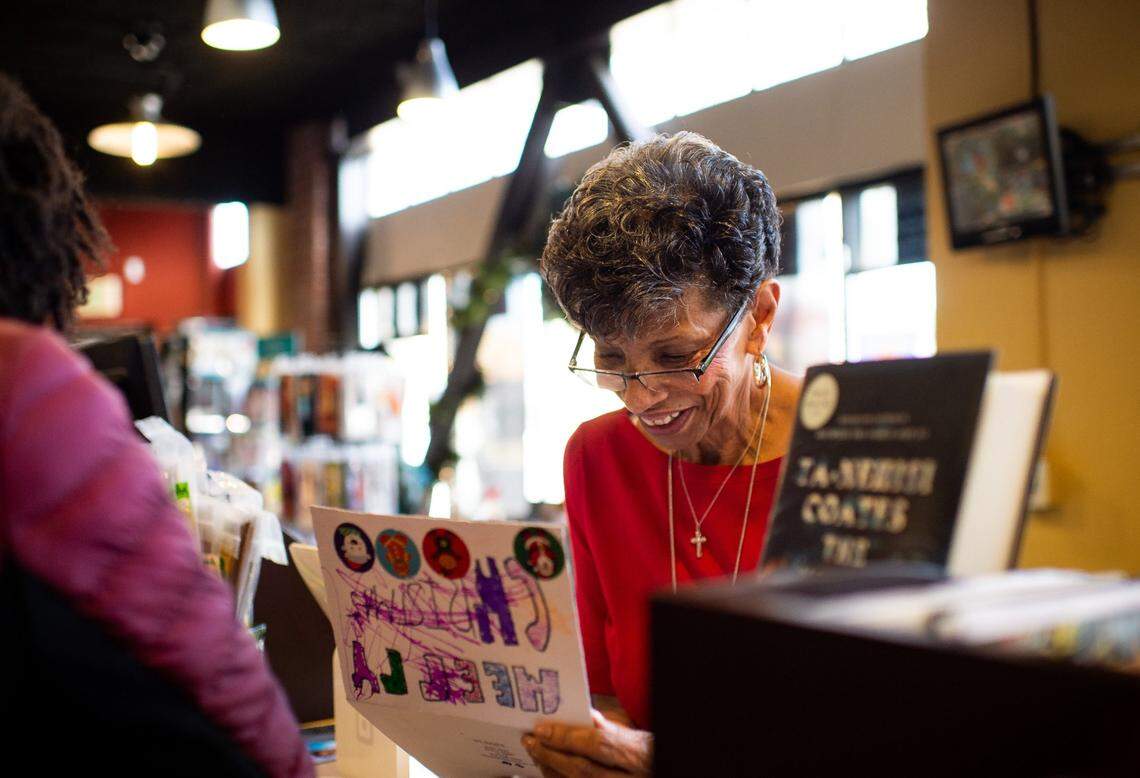 Underground Books manager Georgia West, commonly known as “Mother Rose,” of Oak Park, admires a photo of a child with “Black Santa” during a Christmas in Oak Park event in 2019 at the bookstore and neighboring The Guild Theater.