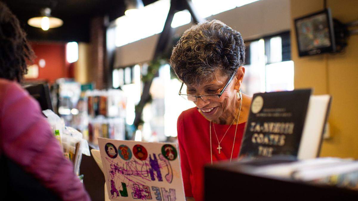 Underground Books manager Georgia West, commonly known as “Mother Rose,” of Oak Park, admires a photo of a child with “Black Santa” during the second annual Christmas in Oak Park event Saturday, Dec. 14, 2019, at the bookstore and neighboring The Guild Theater. “For kids to see a Santa Claus that looks like them for a change ... I mean any Santa is good, but I just think we need some options,” West said. “It’s a diverse community, and so we want diversity, we want everybody to come,” she added, “but I just think, for us, this is a great option and a great event.”