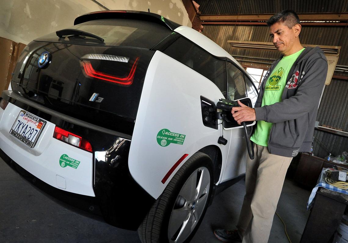 Reyes Barboza Jr., director of operations for Green Raiteros, charges a BMW electric car in 2018.