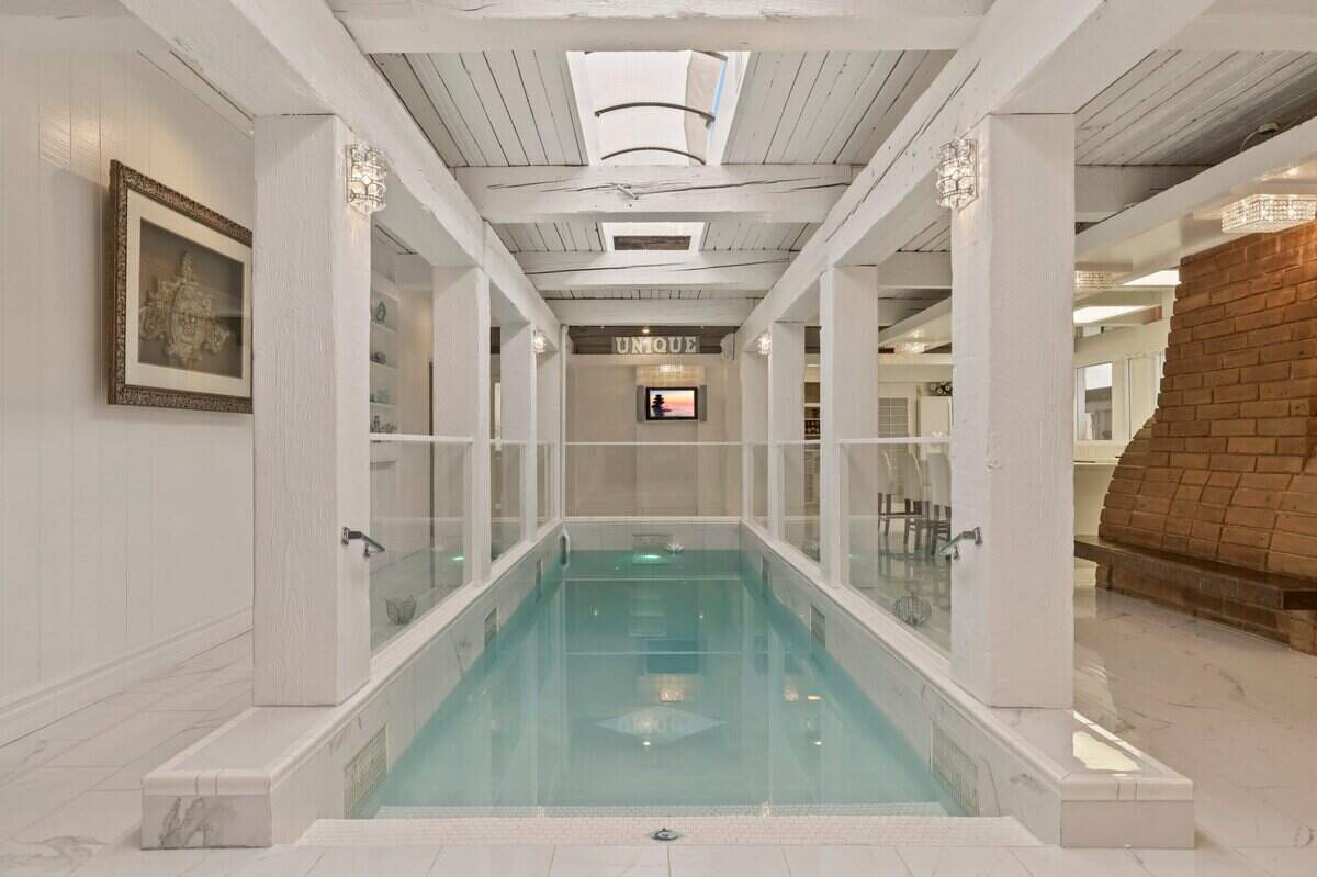 The upgraded indoor pool slopes down to 7 feet in depth and is 27 feet long with a skylight above and the kitchen adjacent.
