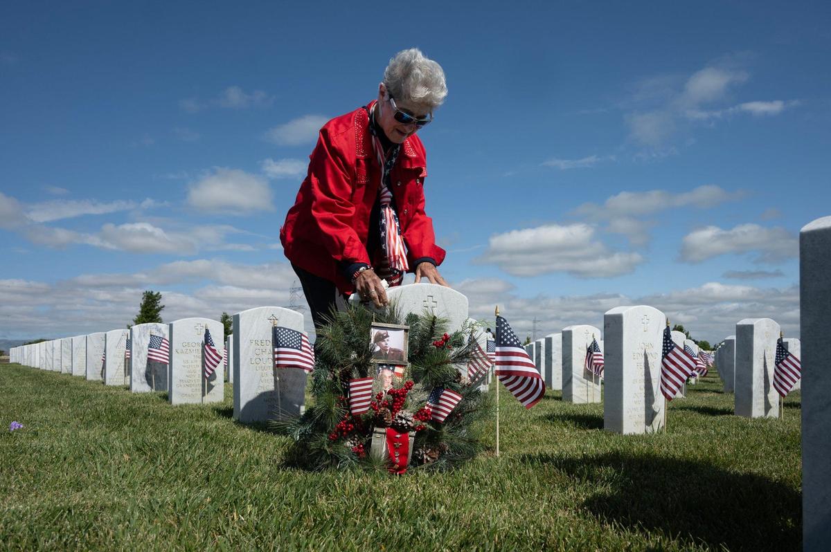 Anna Rodrigo, of Carmichael, lays a wreath with photographs of her husband Manuel at his headstone at the Sacramento Valley National Cemetery in Dixon after its ceremony to mark the Memorial Day holiday on Saturday, May 25, 2024. Manuel served in the Army and Air Force and saw time in Korea. The couple were married 65 years.