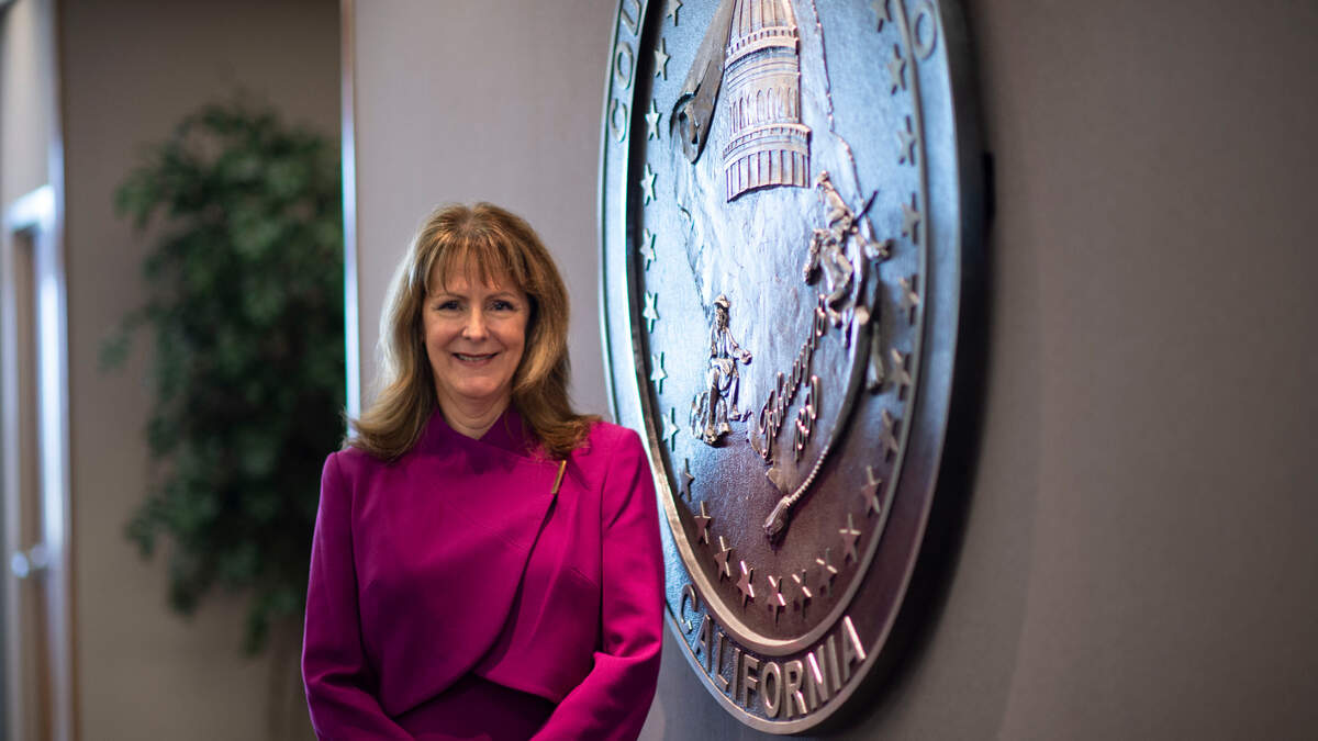 Ann Edwards stands next to the Sacramento County seal at the Board of Supervisors office on Wednesday, Aug. 25, 2021. The Sacramento County Board of Supervisors unanimously agreed to appoint Edwards as the permanent county executive Tuesday. She is the first woman to hold the top administrative role, succeeding Navdeep Gill.
