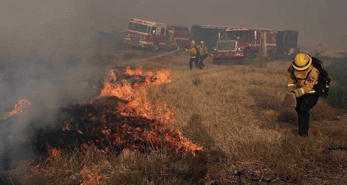 Cal Fire SCU personnel work to cut off flames in the median of Interstate 580 south of Tracy during the Corral Fire on Saturday. The wildfire exploded to more than 12,000 acres burned several structures and shut down an interstate freeway southwest of Tracy. Evacuation orders remain in place.