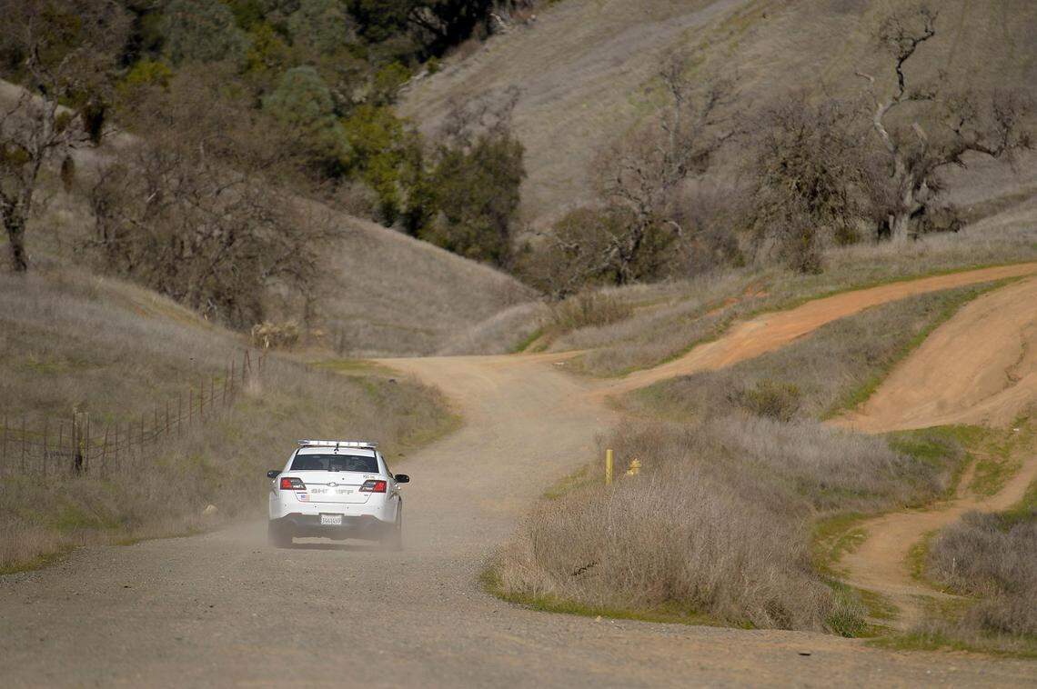 A Lake County Sheriff’s Deputy drives his patrol car along an unpaved rural road.
