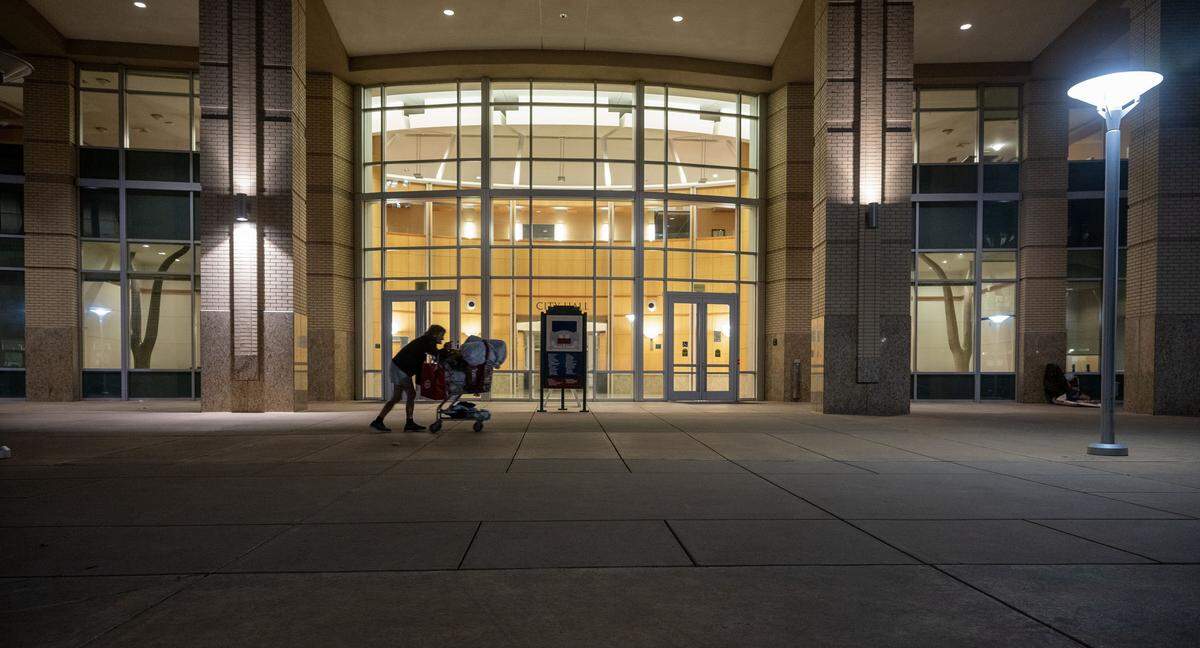 A homeless woman who declined to give her name walks past Sacramento City Hall on Wednesday, Aug. 27, 2025, the last night before an ordinance took effect prohibiting people from sleeping outside the building.
