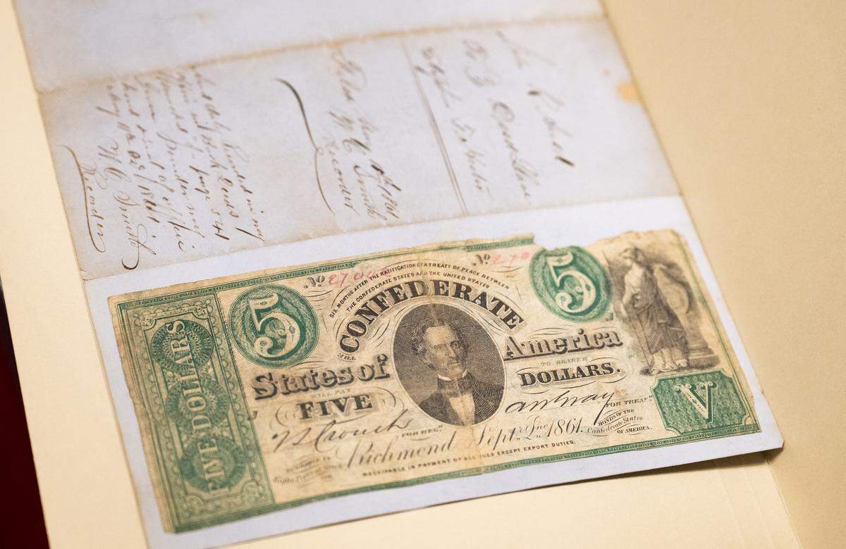 A $5 confederate bill is attached to the back of an 1861 slave deed held in the vault at the California State Library.