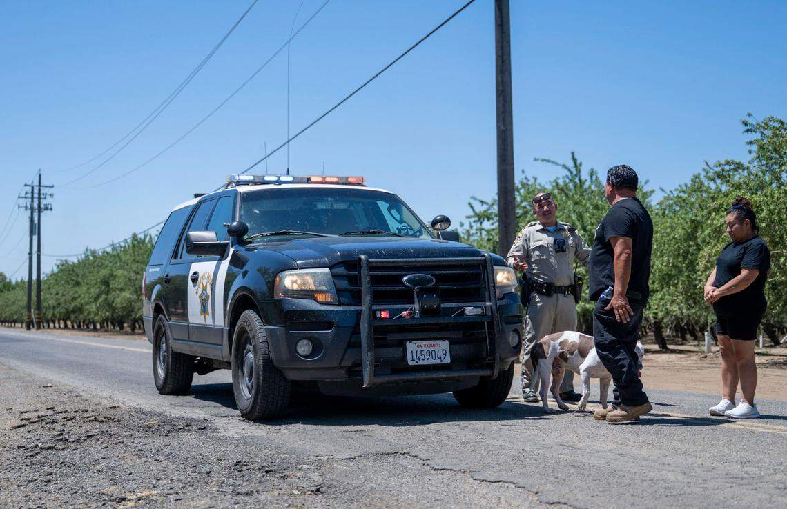 Joel, center, and Marisol Hernandez, right, speak on Wednesday, July 2, 2025, with a California Highway Patrol officer at a road closure near Esparto. They hoped to proceed beyond the barrier on Road 86B to search for a missing family member who was working at a pyrotechnics facility where explosions occurred the night before.